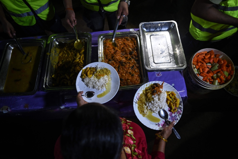 Volunteers serve food to flash flood survivors at a temporary relief camp in Devighat, Nepal’s Nuwakot district as thousands remain missing after the devastating Nepal-Tibet floods.  — AFP pic