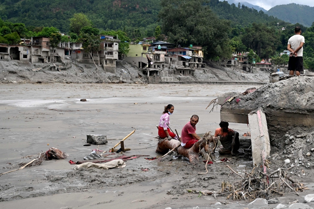 Residents sit beside debris as they salvage belongings following flash floods at Devighat in Nepal’s Nuwakot district August 31, 2026. — AFP pic