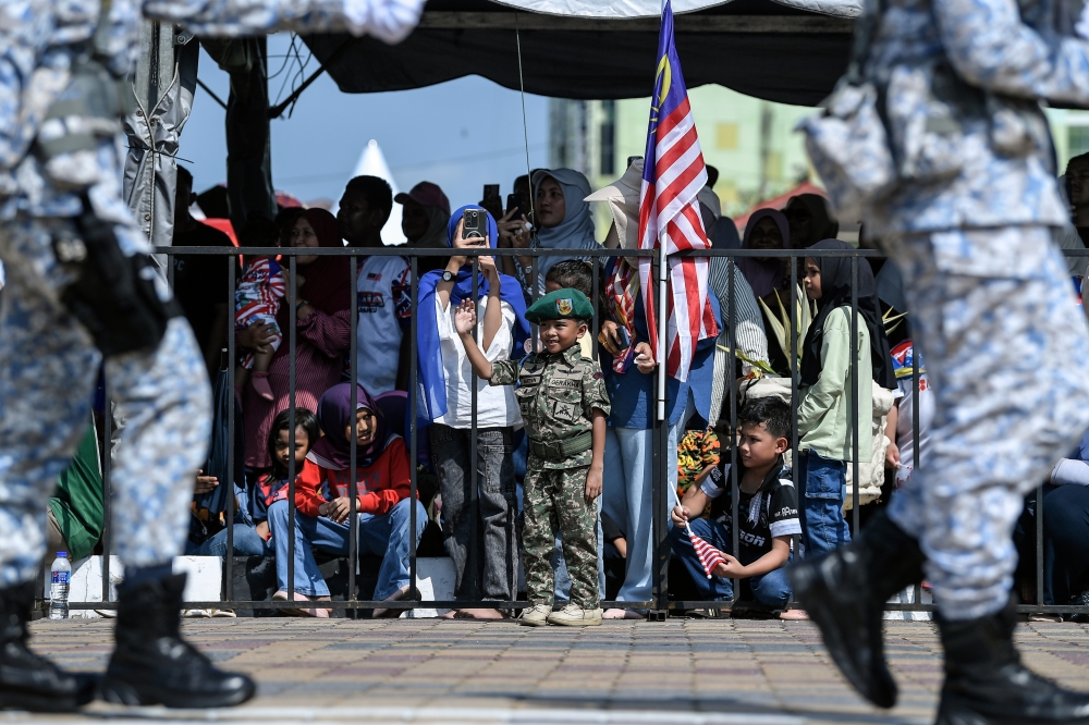 A young boy in Malaysian Armed Forces uniform waves during the Kedah‑level 69th National Day parade at Dataran Medan Bandar. — Bernama pic