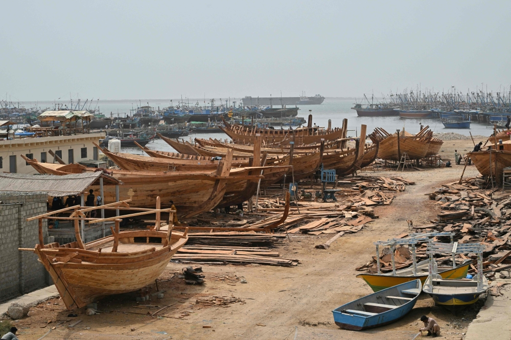 This photograph taken on July 8, 2026 shows traditional wooden boats at a yard in Ibrahim Hyderi in Karachi. The rhythmic hammering of nails and the whine of saws echo around a coastal Karachi neighbourhood, where small figures of men work atop massive wooden fishing hulls that loom beneath a pale summer sky. Despite the rise of industrial shipbuilding, such practices -- where handcrafted vessels are assembled timber by timber -- have stood their ground. — AFP pic