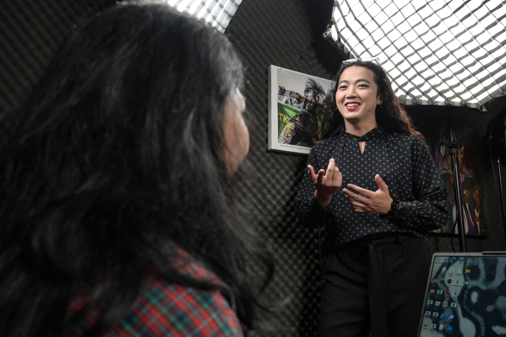 Transgender woman and activist Dania Joedo chats with a colleague at her office in Jakarta on August 13, 2026, amid growing anti-LGBTQ sentiment in Indonesia. — AFP pic