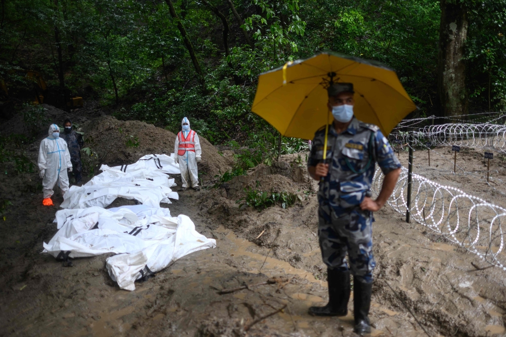 Security personnel stand next to unidentified bodies of flood victims kept for mass burial at the Gokarna forest reserve in Kathmandu on September 1, 2026. — AFP pic