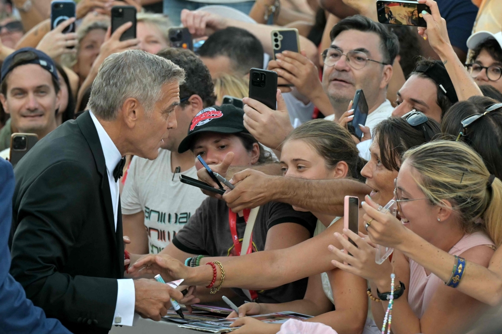 Actor and filmmaker George Clooney (left) signs autographs during the red carpet event ahead the screening of ‘Ink’ and the opening ceremony of the 83rd International Venice Film Festival, at Venice Lido on September 2, 2026. — AFP pic