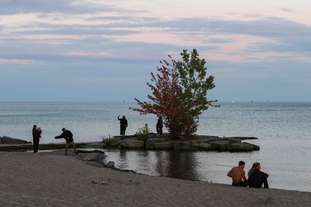 People gather at dusk on the shore of Lake Ontario in Toronto, Ontario, on August 27, 2026. — AFP pic