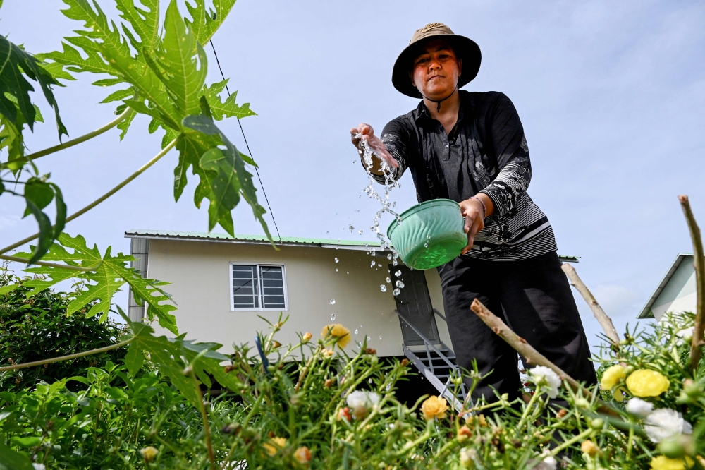 Villager Ang Sophat, 42, watering vegetables outside her house in a 