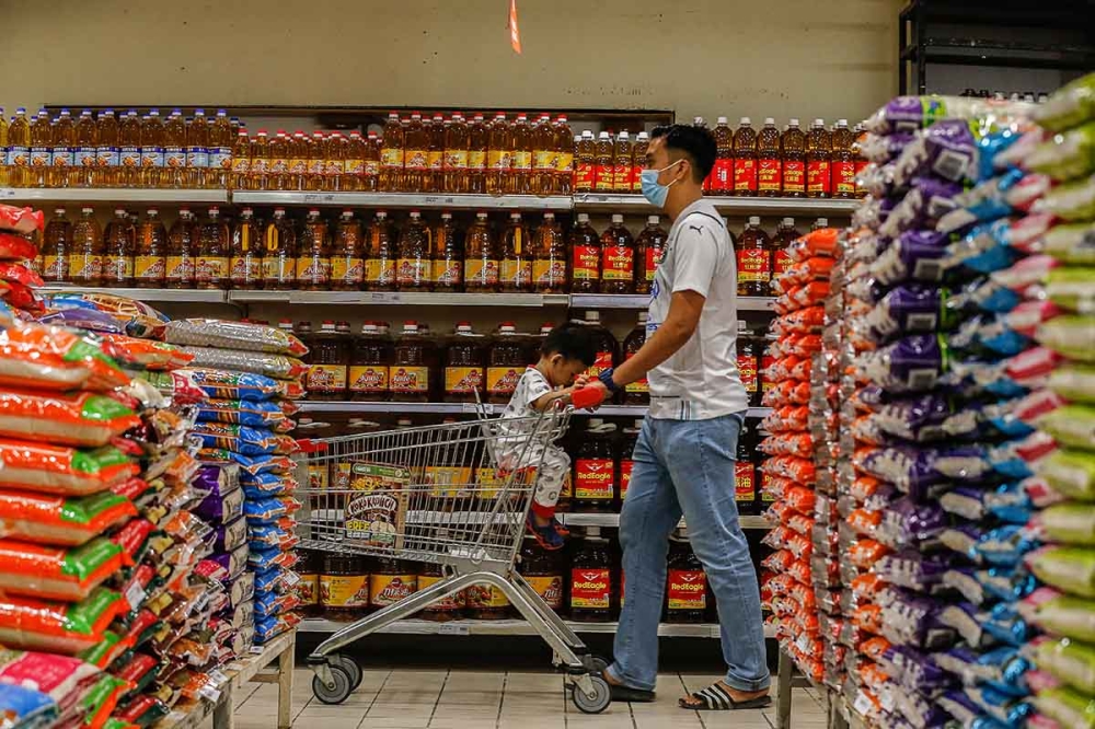 A family walks past cooking oil shelves while shopping at a supermarket in Penang. — Picture by Sayuti Zainudin