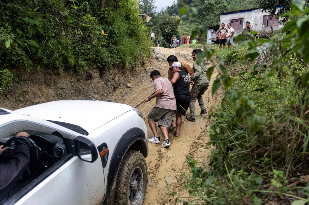 People help a vehicle navigate a damaged, muddy road leading to remote Rasuwa after flash floods in Nepal’s Nuwakot district on September 4, 2026.  — AFP pic