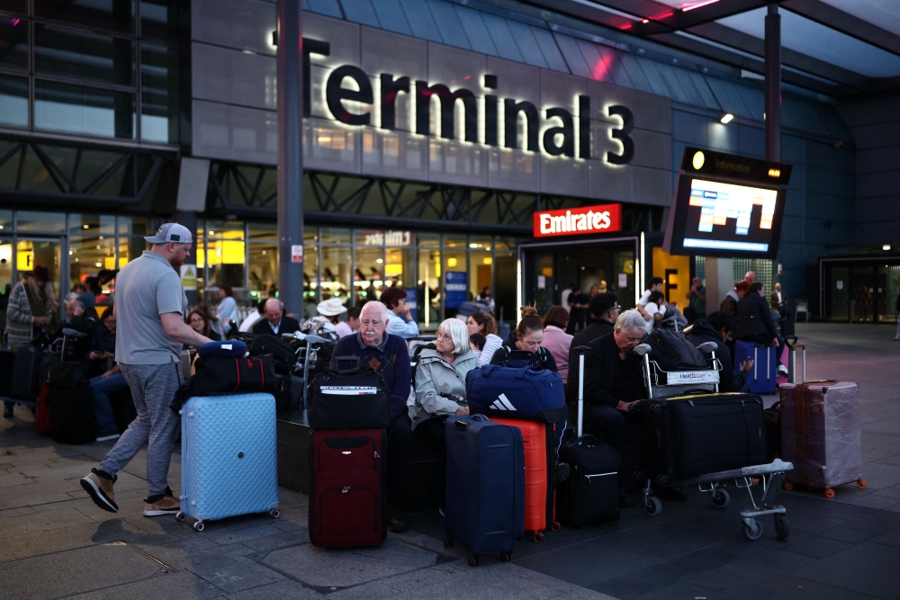 Passengers sit with their luggage outside Terminal 3 of London Heathrow airport, west of London on September 8, 2026, following major disruption due an issue affecting the NATS air traffic control systems. — AFP pic