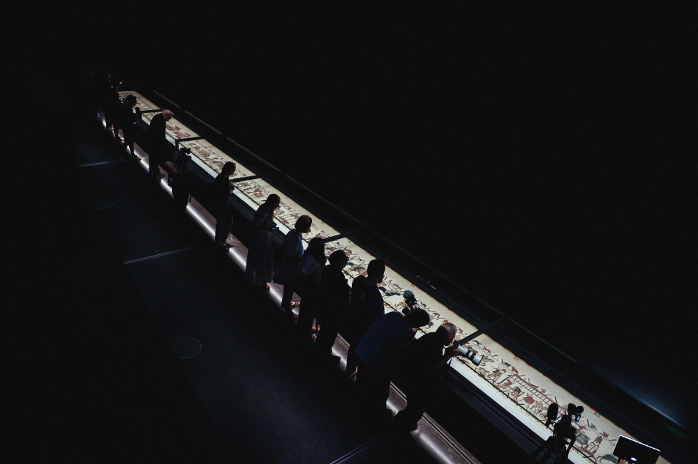 People lean over the display case to take a closer look at the Bayeux Tapestry during a media preview ahead of the official opening at the British Museum in central London on September 7, 2026. — AFP pic