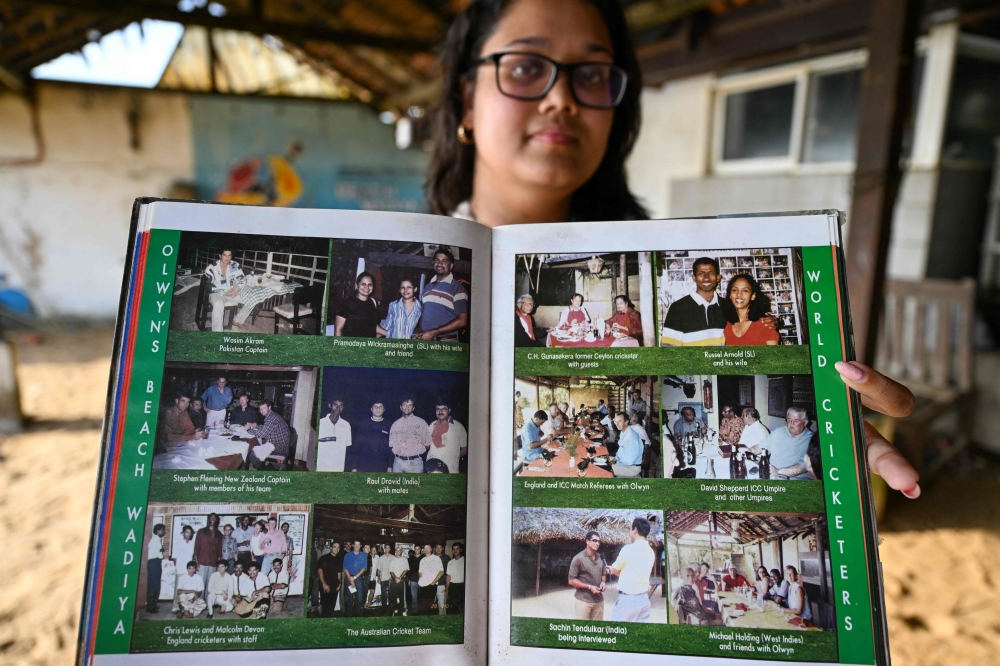 Co‑owner Suhara Chandrasekera shows a celebrity photo album at Colombo’s Beach Wadiya shack. — AFP pic