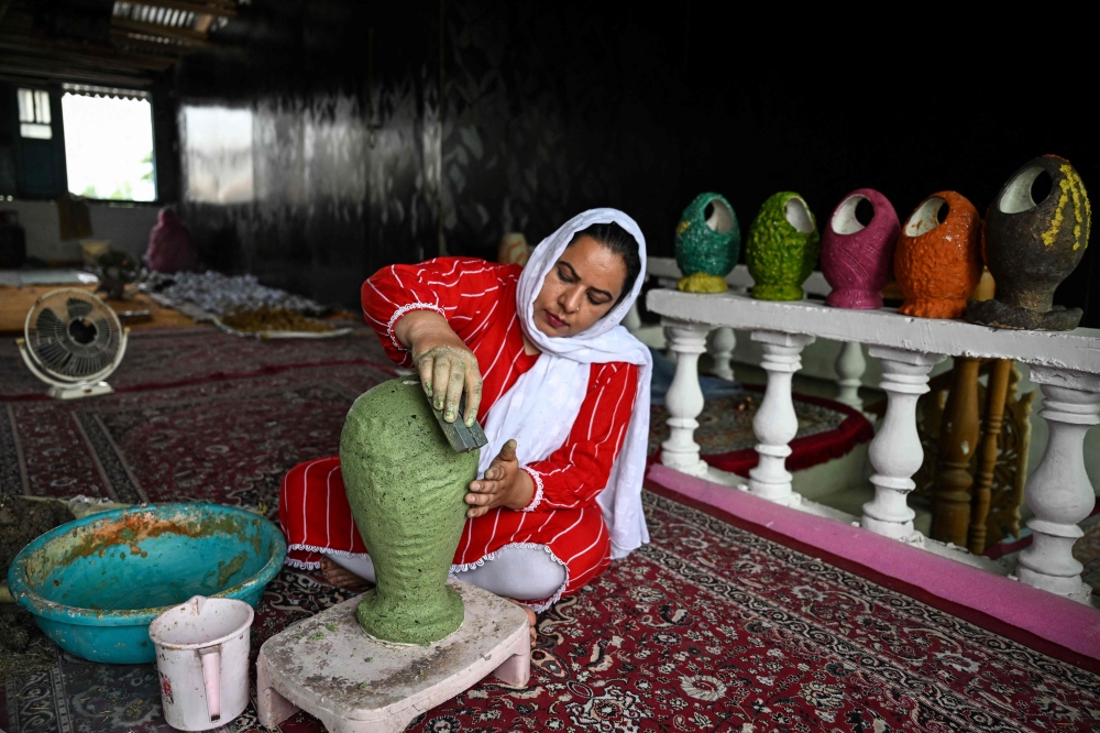 A Kashmiri artisan uses dried aquatic weeds and grass collected from Dal Lake to create sustainable handcrafted papier-mache at a workshop in Srinagar on August 19, 2026. — AFP pic