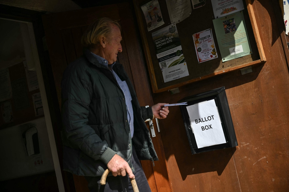A resident places his ballot in a box at the local village hall in Piddington, Oxfordshire, north-west of London on September 15, 2026, as the town of fewer than 400 inhabitants votes on a symbolic referendum on leaving the UK. — AFP pic