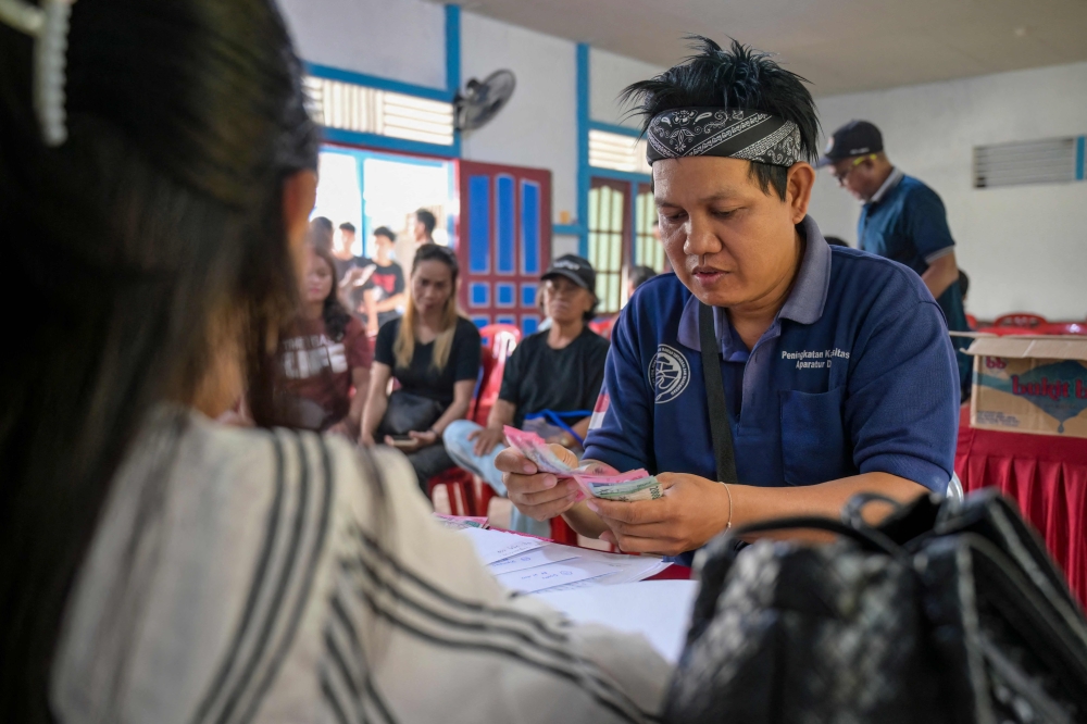 Borneo Future Indonesia wildlife observer Diyonisius receiving payment for observation activities in Labian village in Kapuas Hulu, West Kalimantan. Indonesian as part of a conservation programme seeking to make animals worth more alive than dead. — AFP pic