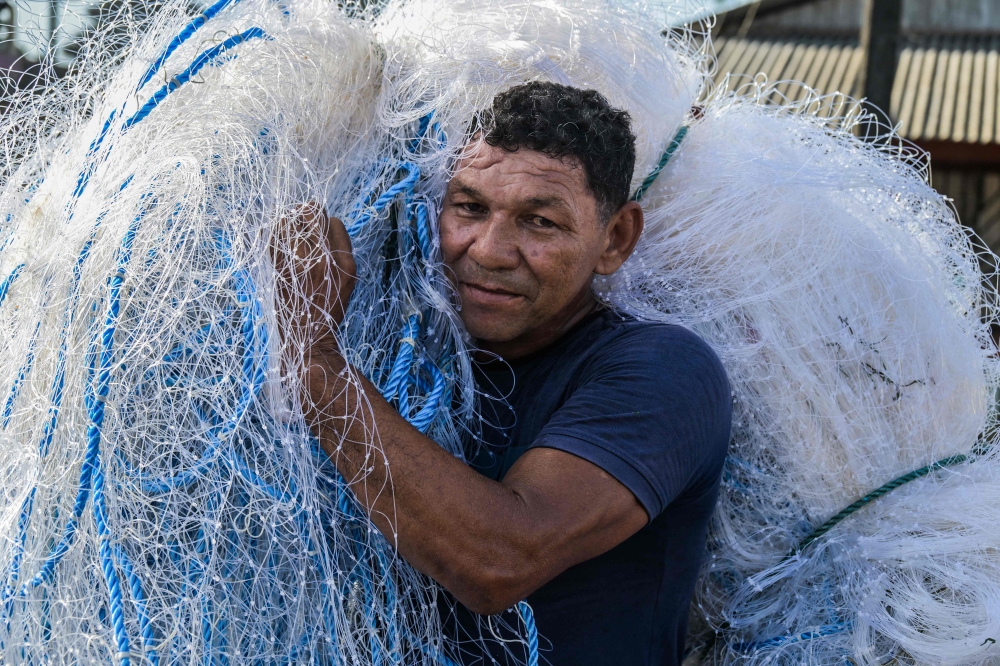 A fisherman carries a fishing net in Oiapoque, Amapa state, Brazil on September 3, 2026 where residents are caught between hopes of an economic boom and fears of an oil spill. — AFP pic