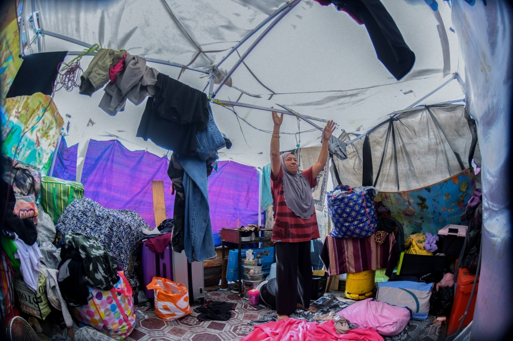 Fire victim Rohaida Absara, 53, repairs her tent after it was torn by strong winds during a recent check on the temporary settlement. — Bernama pic