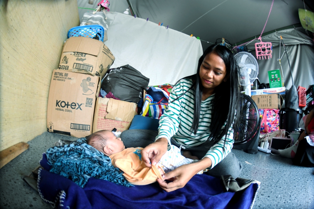 Simang Damli, 31, shelters in an overcrowded tent with three other families in Sandakan, keeping only her one-month-old baby with her after sending five children to stay with relatives. — Bernama pic