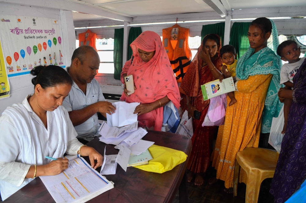 Women register their child for vaccination inside a mobile boat clinic in the Mukalmua village of Assam’s Nalbari district September 19, 2026. — AFP pic