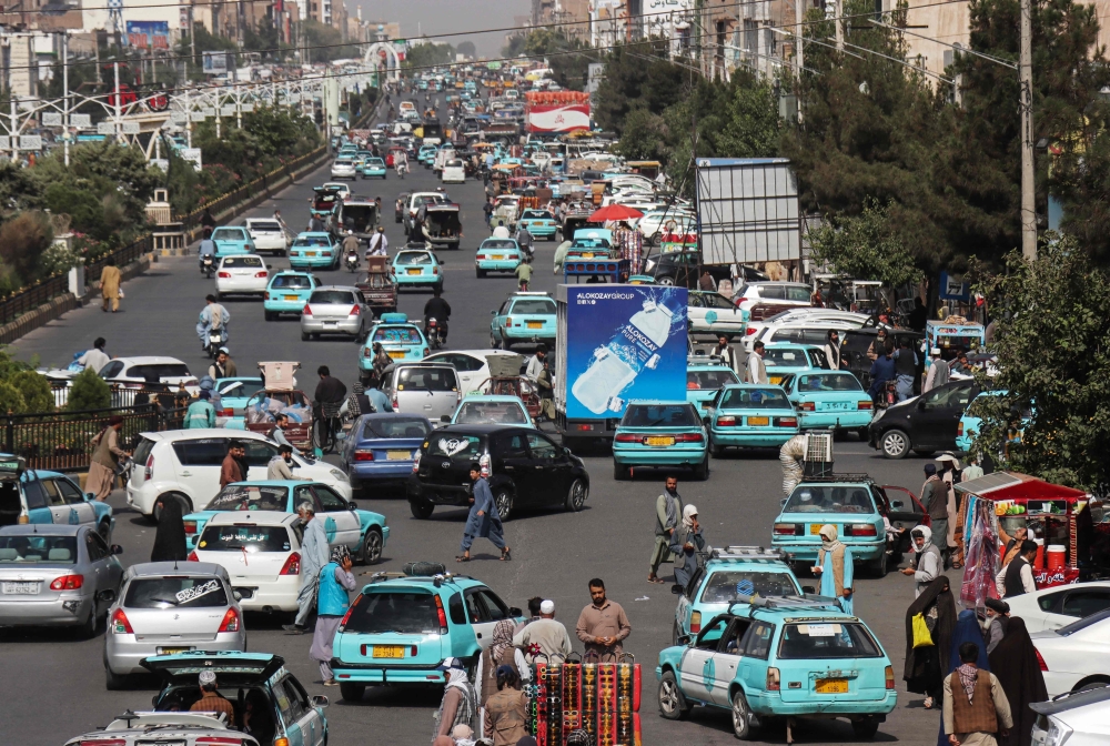This photograph taken on July 1, 2026 shows commuters riding blue taxis at a square in Herat. The music that used to flow constantly out of restaurants, cafes and shops in the capital Kabul has been muted for five years, replaced only by religious or patriotic songs supported by the Taliban authorities in power since 2021. — AFP pic
