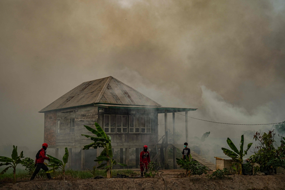 Thick acrid smoke from a nearby wildfire engulfs a rural stilt-supported wooden house in Ogan Ilir, South Sumatra province on September 25, 2026. — AFP pic