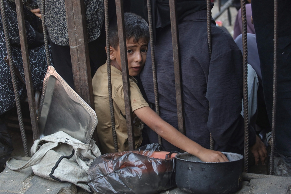 A displaced Palestinian boy waits with others to receive hot meals distributed by a charity kitchen in Khan Yunis in the southern Gaza Strip on September 25, 2026. — AFP pic