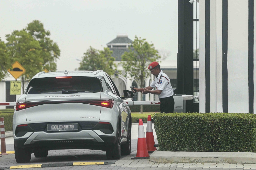 A security guard attends to a motorist at the entrance to a guarded residential neighbourhood. Guarded-community schemes remain subject to local authority rules on access and security procedures. — Picture by Sayuti Zainudin