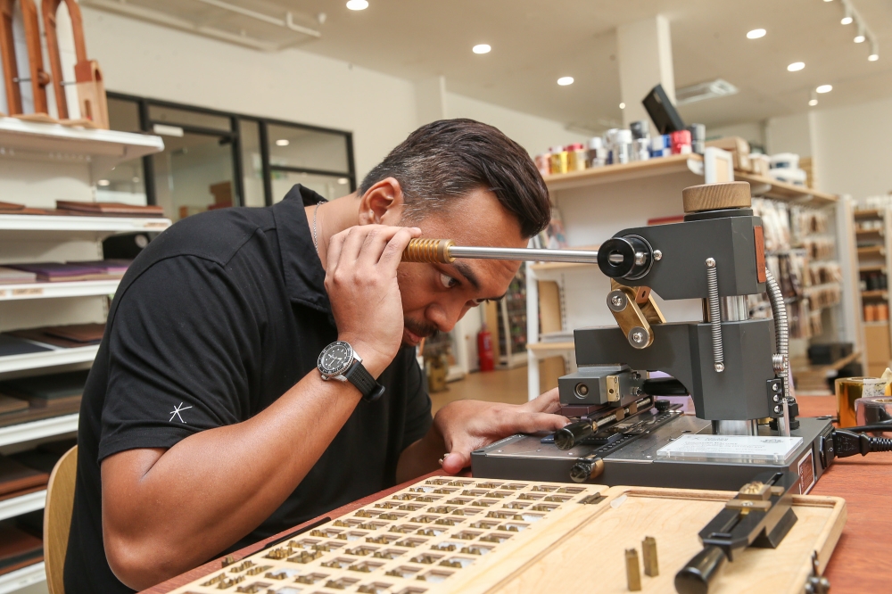You can personalise your leather craft with your initials, as Kelang Leather team member Armand Rastam is seen doing here. — Picture by Choo Choy May