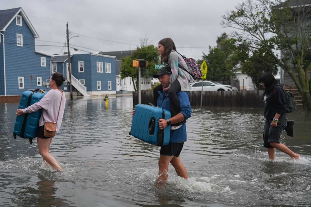A family carries their belongings through floodwaters during a nor’easter in Point Pleasant, New Jersey, September 26, 2026. — AFP pic