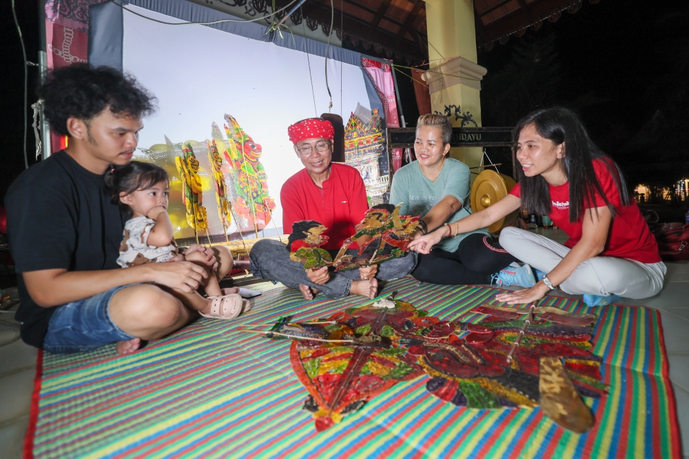 Kelantan ‘wayang kulit’ practitioner and Sri Cindayu Wayang Kulit Association founder Kang Boon Ann, 58, with his wife Eh Tian Eh Awang, 52, (second, right) and their children Kang Siew Lie, 32, (right) and Kang Xiau Ren, 29, (left), look at ‘wayang kulit’ characters used during a performance at Tok Bali Jetty, Pasir Puteh, recently. — Bernama pic