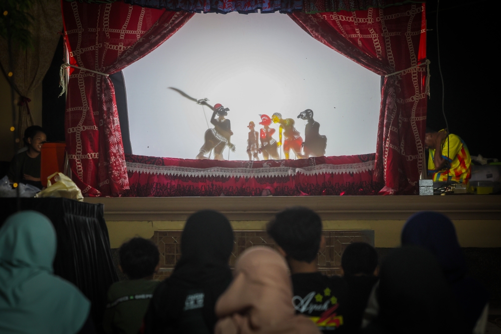 Spectators watch a ‘wayang kulit’ performance by Sri Cindayu Wayang Kulit Association founder Kang Boon Ann, 58, at Tok Bali Jetty, Pasir Puteh, recently. — Bernama pic 