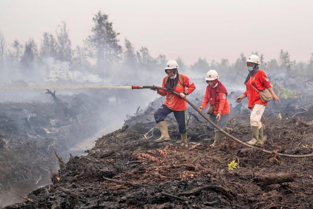  Members of the all-women The Power of Mama (TPoM) volunteer firefighting team spray water onto smouldering peatland in Mensubuk Lama, Tanjungpura Village, Ketapang Regency, West Kalimantan on September 26, 2026. — AFP pic