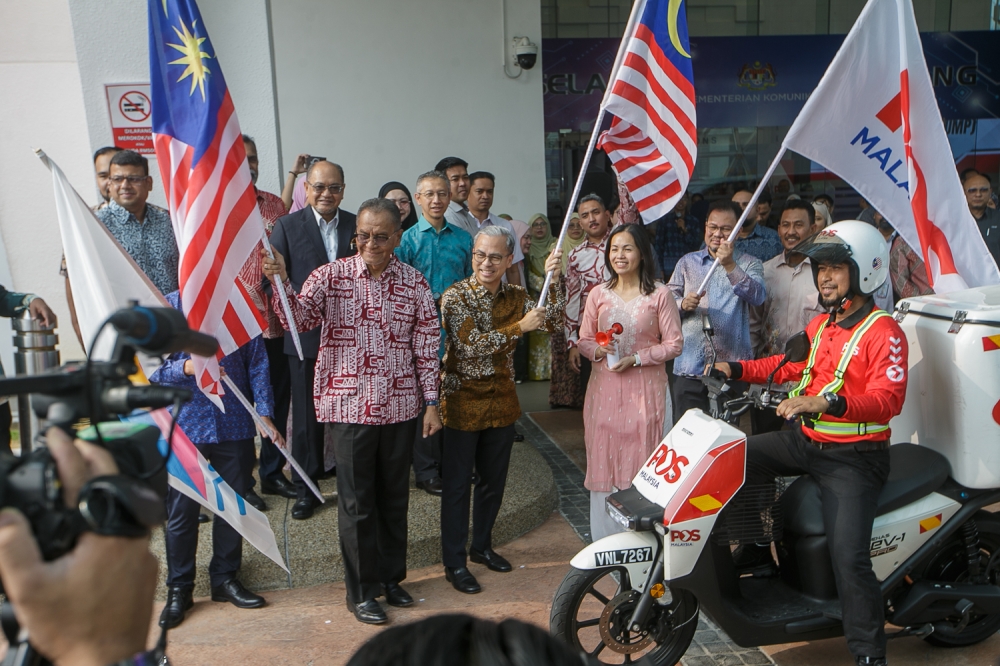 Communications Minister Datuk Seri Fahmi Fadzil waves the Jalur Gemilang to flag off a Pos Malaysia delivery rider, accompanied by Deputy Communications Minister Teo Nie Ching and Health Minister Datuk Seri Dr Dzulkefly Ahmad, during the launch of the Medicine Delivery via Post (UMP) Funding Initiative at the Communications Ministry in Putrajaya, September 29, 2026. — Picture by Raymond Manuel