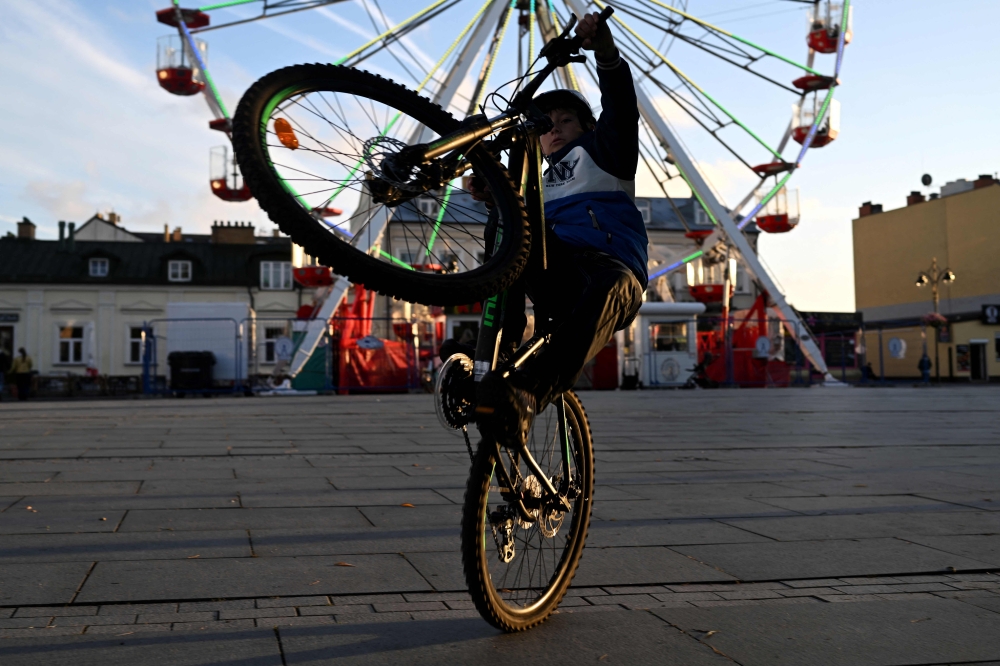A child rides a bicycle in front of a Ferris wheel in Suwalki, Podlaskie Voivodeship, Poland, near the Suwalki Gap on September 26, 2026. — AFP pic