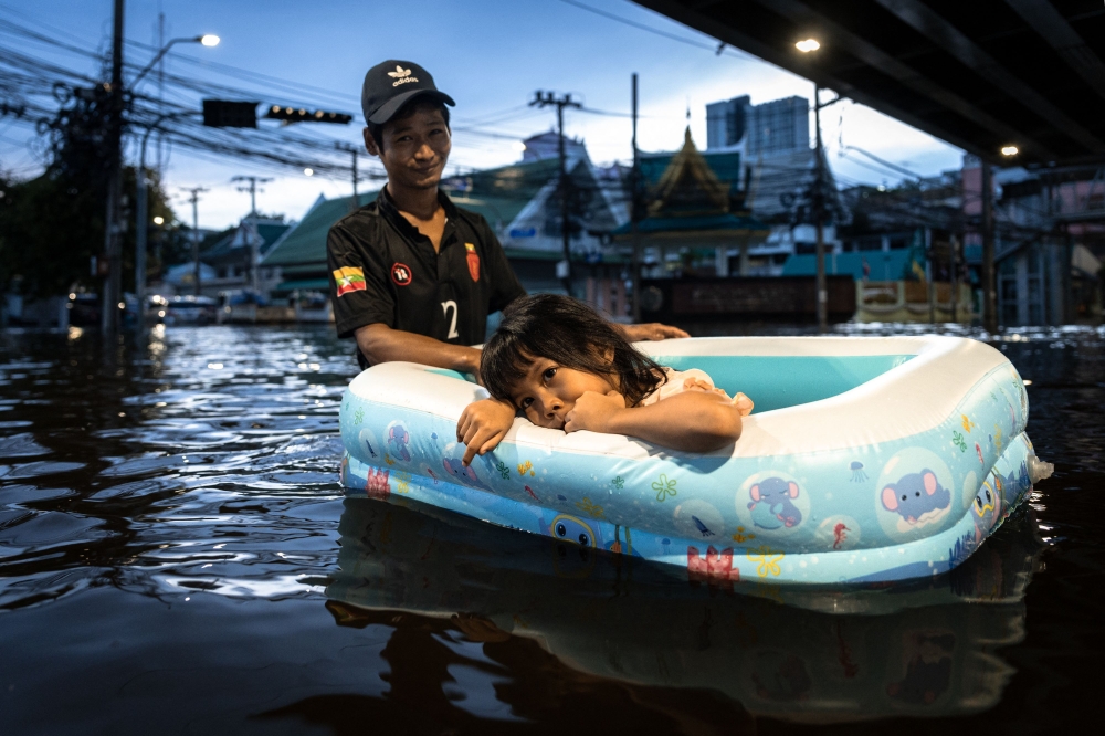 A man pulls a girl in an inflatable boat through floodwaters in the Bang Kapi district of Bangkok, Thailand on September 28, 2026. — AFP pic