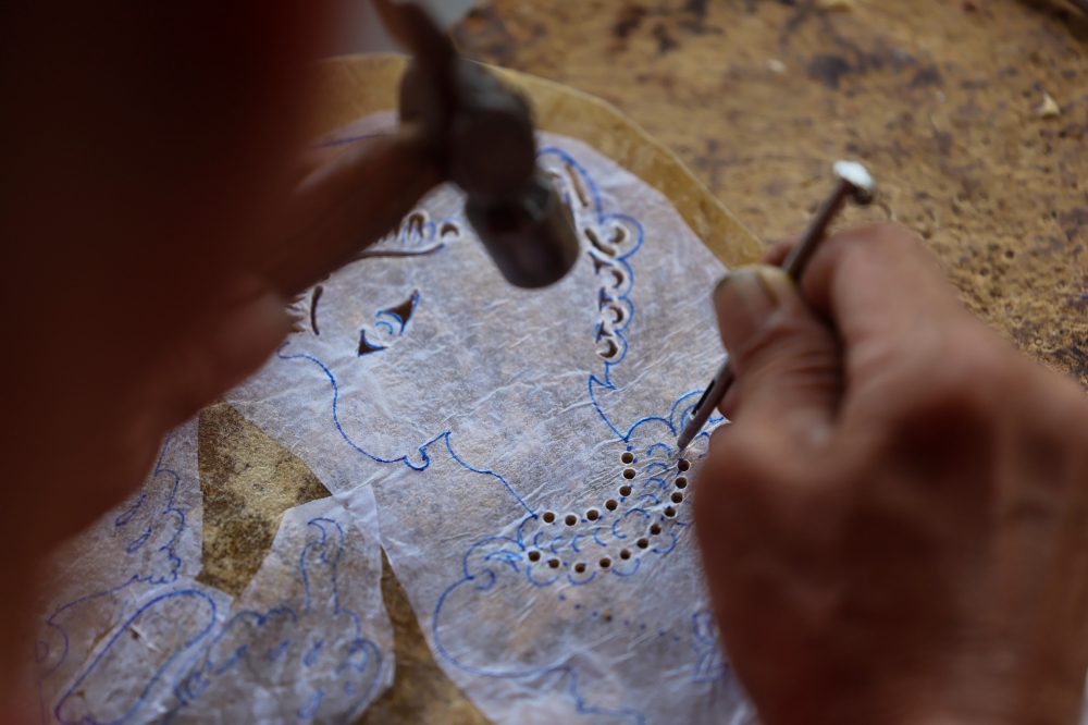 Using only nails of various sizes and a metal hammer, Kang Boon Ann—a practitioner of Kelantan *wayang kulit* (shadow puppetry)—punches thousands of tiny holes into the leather surface to create floral motifs, traditional costumes, crowns, and the various accessories that define each character's identity.While the tools used may be simple, every perforation requires meticulous care, as even a minor error could compromise the entire carved design. — Bernama pic