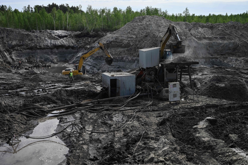 Workers extract amber at the official open cast mine in the Rivne region. — AFP pic