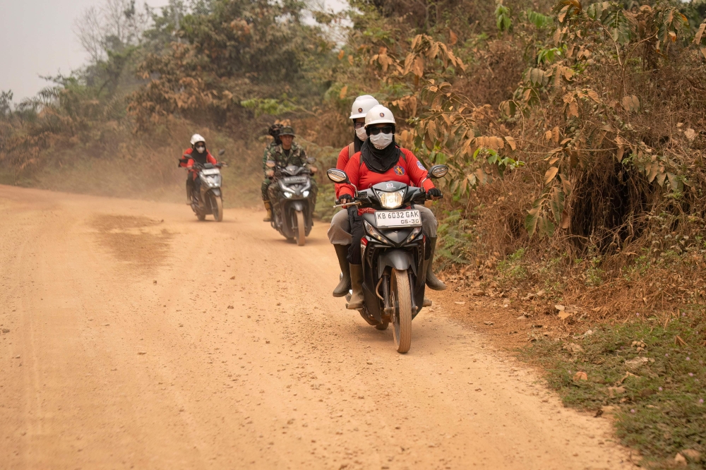 The women setting out, some on motorbikes, others piled onto the back of a pickup truck with a water pump and some buckets. — AFP pic