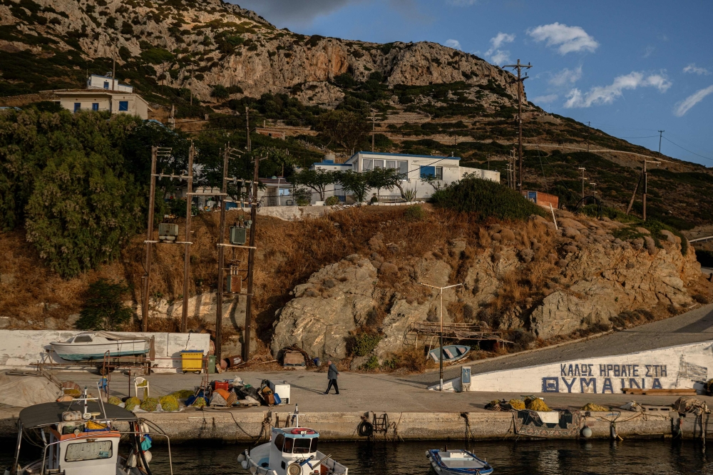 A local walks along the port on the Aegean island of Thymaina.