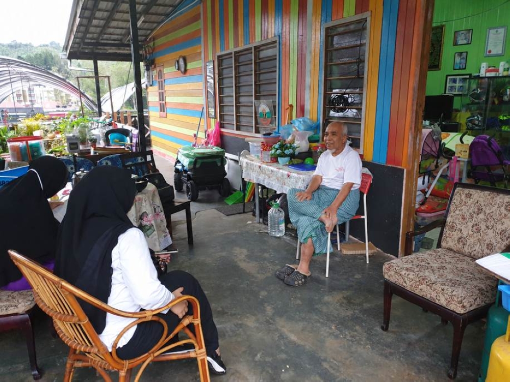 Listening to the stories of a Kampung Taman Sedia resident about the history of Cameron Highlands, the local community and how local businesses have evolved over the years. — Picture by Nadiah Mahmad Nasir