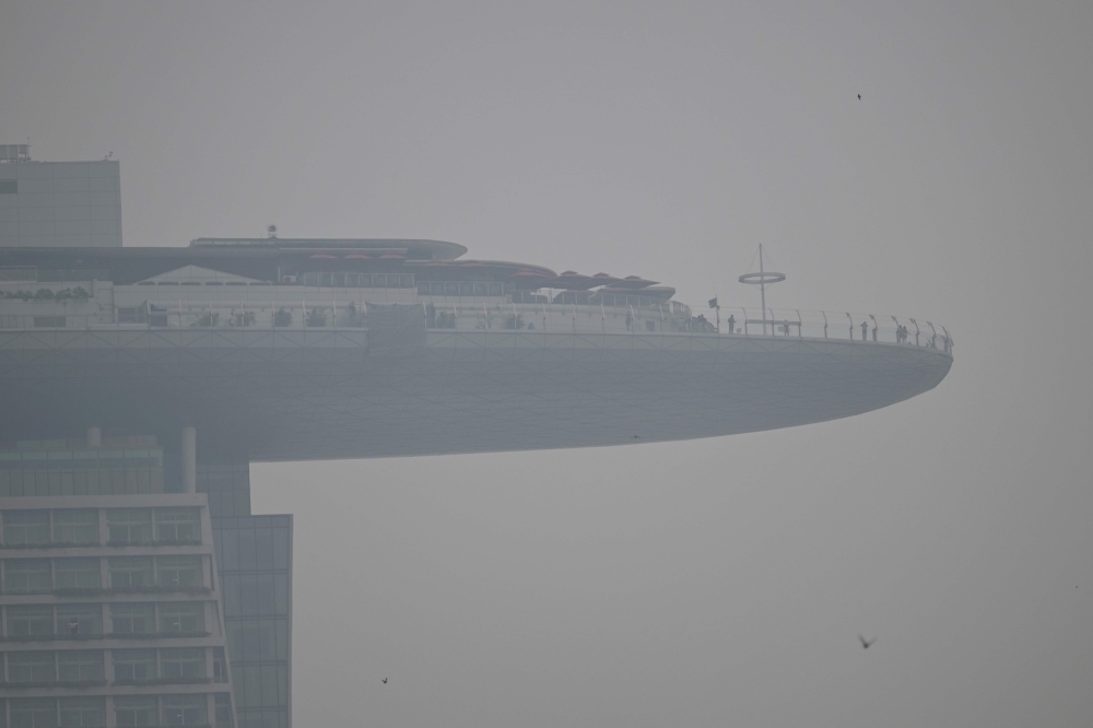 People stand on the observation deck of the Marina Bay Sands on a hazy day in Singapore September 28, 2026. — AFP pic