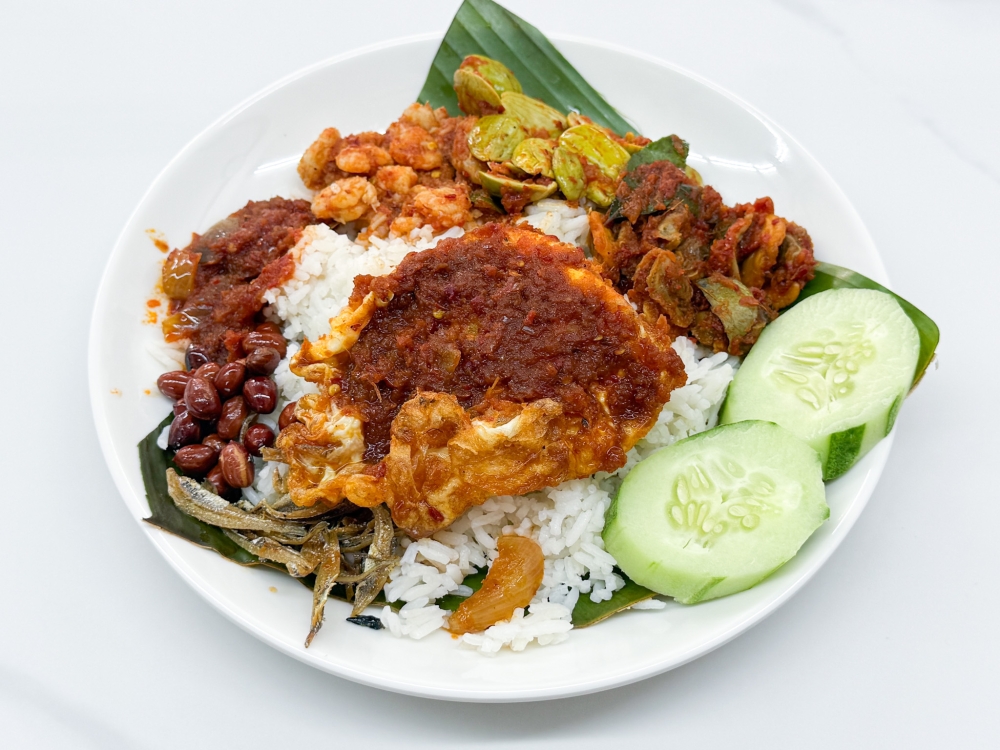 Should you prefer the conventional way to eat ‘nasi lemak’ with ‘ikan bilis’ and peanuts, ask for it plated and topped with ‘petai’, baby prawns, clams and a ‘sambal’ fried egg. — Picture by Lee Khang Yi