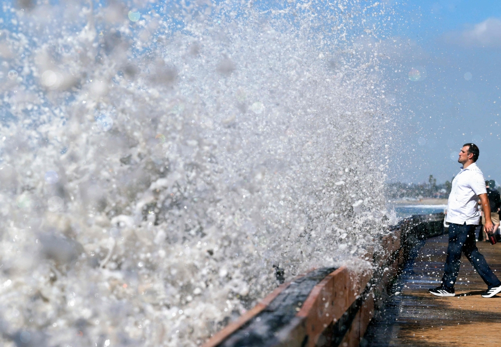 A person watches as a Pacific Ocean wave crashes into a seawall protecting beachfront homes on September 28, 2026 in Long Beach, California. Heavy surf generated by Hurricane Polo offshore, amid a Pacific Ocean heatwave and an emerging El Nino, led to a coastal flood advisory from the National Weather Service for much of Southern California. — Mario Tama/Getty Images North America/Getty Images pic via AFP