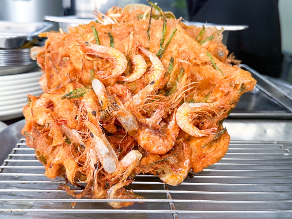 After frying the snacks, the Cucur Udang is left on the rack to allow excess oil to drip off. — Picture by Lee Khang Yi