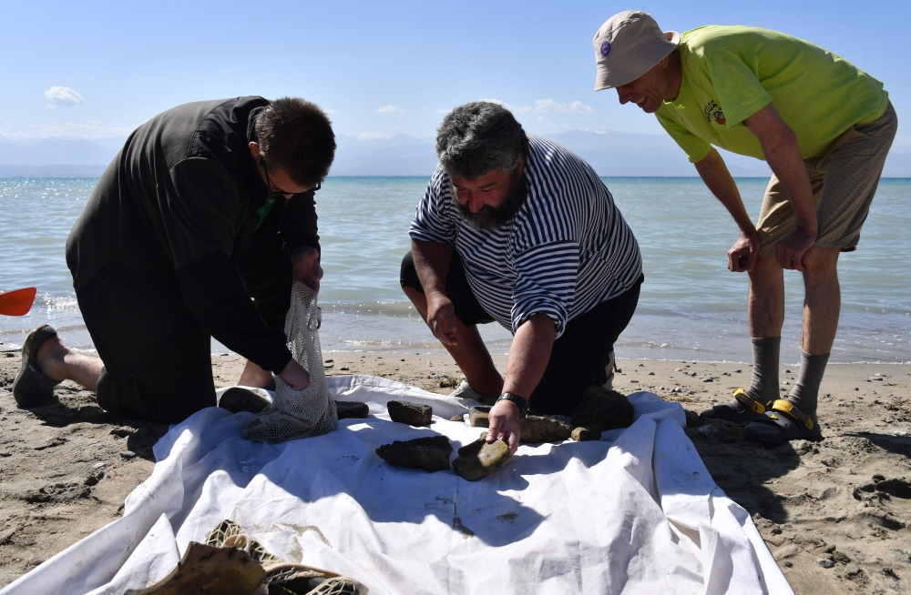 Maxim Menshikov, archaeologist and the expedition director, and fellow colleagues inspect the finds discovered by divers at the underwater site on the bed of Lake Issyk-Kul of what is identified by researchers as a submerged medieval city on the Silk Road in the settlement of Toru-Aygyr in Kyrgyzstan on September 22, 2026. Situated on an ancient trading route between China and Europe, little is known about the history of the settlement under Kyrgyzstan's largest lake or how it came to be flooded an estimated 800 years ago. The settlement is located at the heart of what was once the Silk Road, a trading route that linked China to the Mediterranean from the 2nd century BC until the mid-15th century. — AFP pic