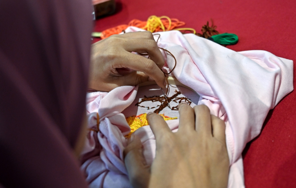 A participant with a learning disability painstakingly works on an intricate embroidery design. — Bernama pic 
