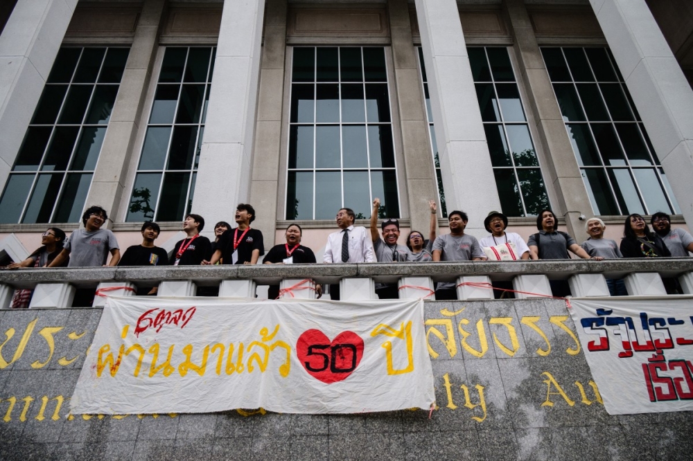 Attendees stand above a banner displayed to mark the 50th anniversary of the Thammasat University massacre on October 6, 1976, during the annual commemoration ceremony for the event at Thammasat University in Bangkok on October 6, 2026. — AFP pic