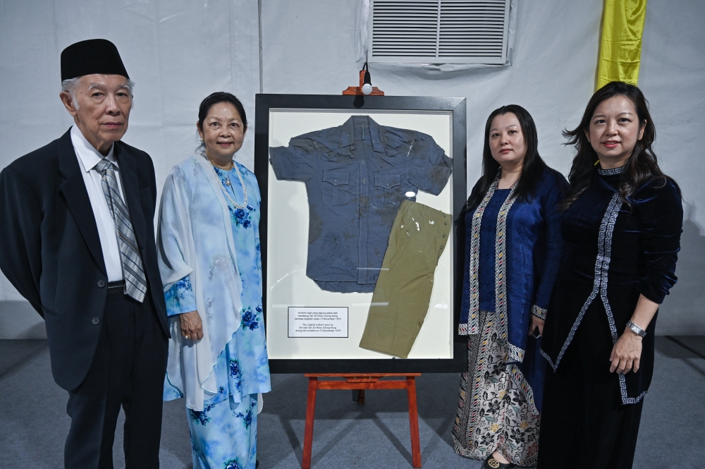 Datin Rita Koo Swee Kim (second left), daughter of the late former Perak police chief Tan Sri Koo Chong Kong, poses with her husband and child beside the original uniform worn by Koo when he was shot dead by communist elements on November 13, 1975, at an exhibition in Ipoh on October 6, 2026. — Bernama pic