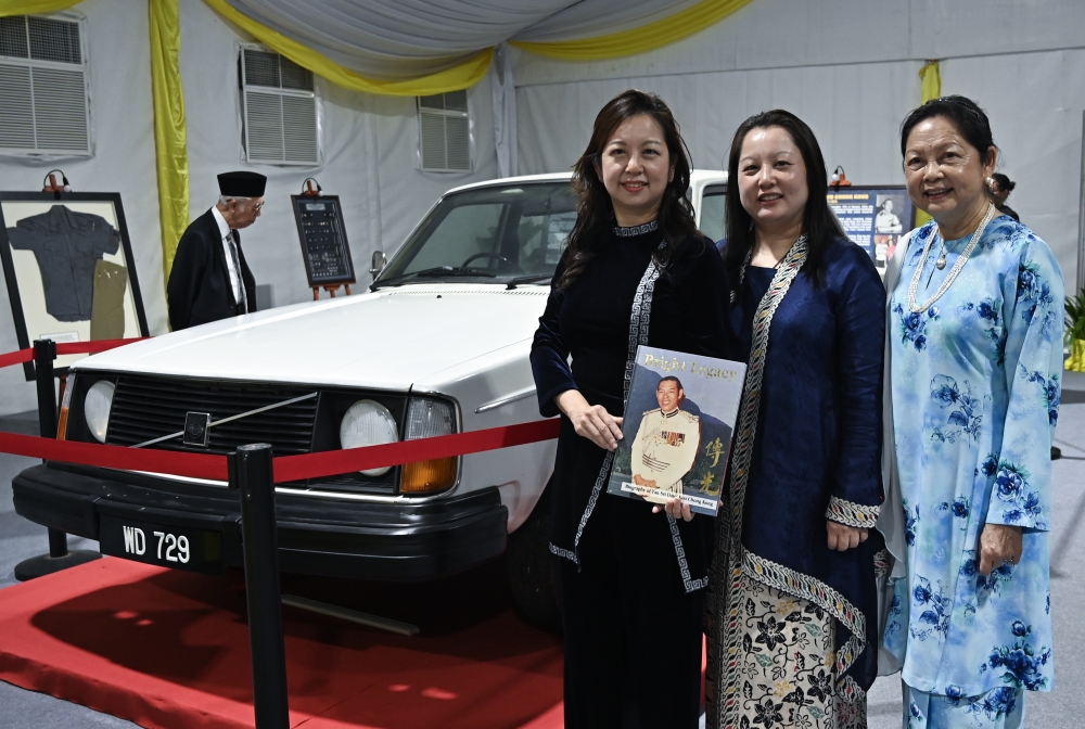 Beside the official car once used by her late father, former Perak police chief Tan Sri Koo Chong Kong, Datin Rita Koo Swee Kim (right) poses with her child at an exhibition in Ipoh on October 6, 2026. Koo was shot dead by communist elements on November 13, 1975. — Bernama pic