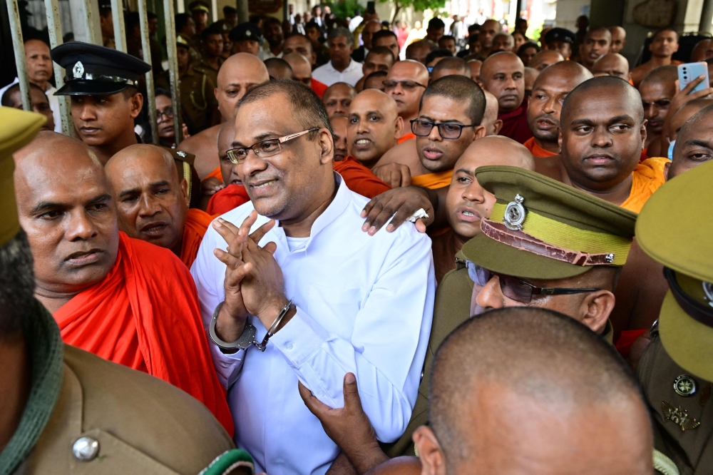 Prison officers escort Buddhist monk Galagodaatte Gnanasara (centre) back to jail, who is under arrest for intimidating the wife of a missing cartoonist, at the High Court in Colombo October 7, 2026. — AFP pic