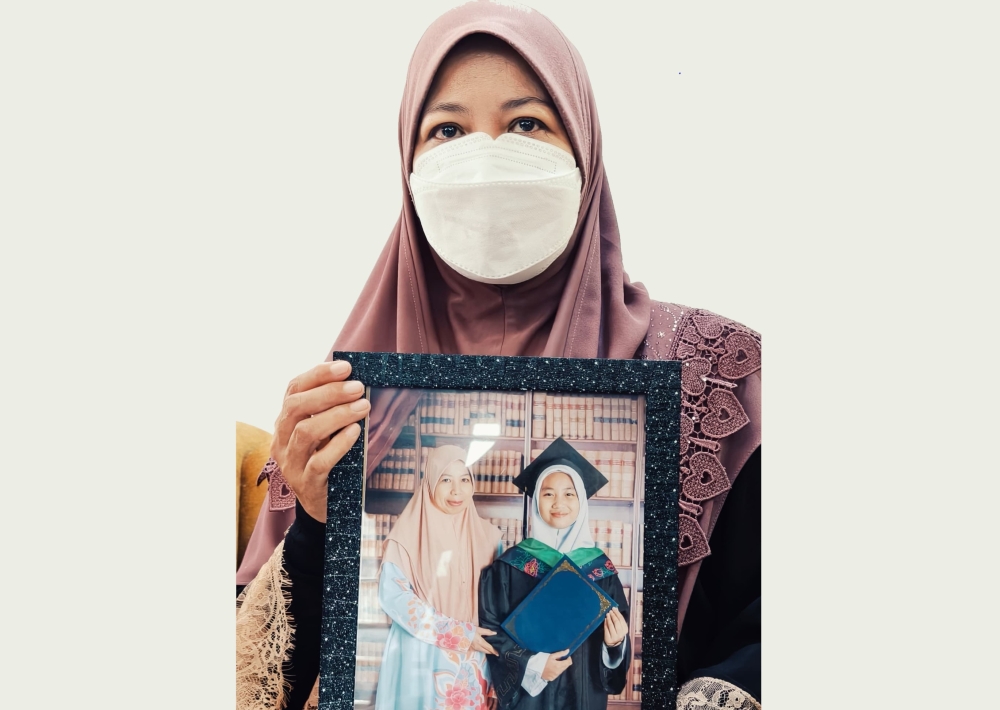 Noraidah Lamat poses with a photo of her daughter, Zara Qairina Mahathir, who succumbed to her injuries a day after being found unconscious near her school dormitory on July 16. — The Borneo Post pic