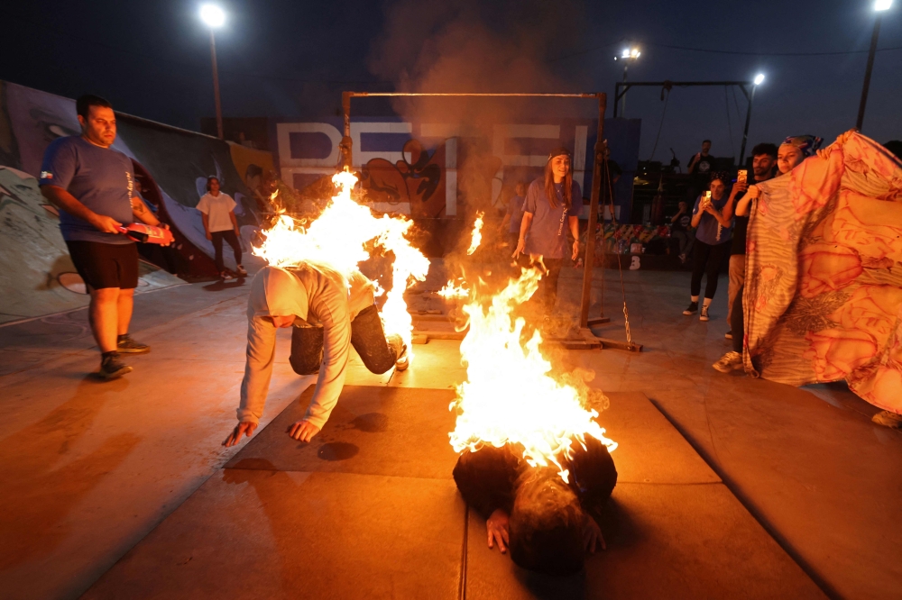 Iranian coach and stunt woman Nasrin Teymouri (center R) teaches fire techniques to stunt performers Mojgan Nematollahi (C) and Arshia Teymouri (L) during a training session in in Tehran's skatepark, in the capital on September 25, 2026. — AFP pic